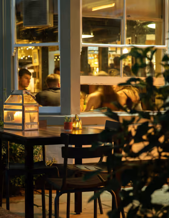 pub exterior with lights and plants and people eating inside