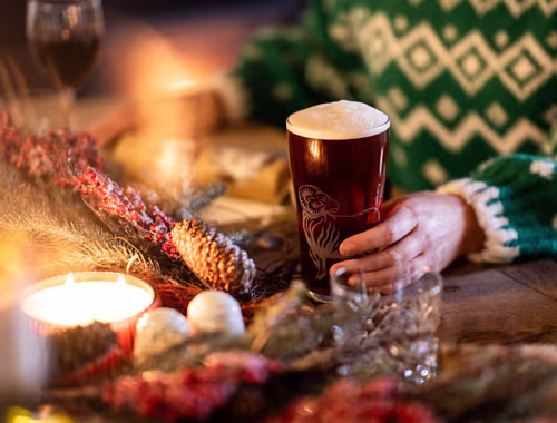 person holding a pint of Young's beer at a festive table