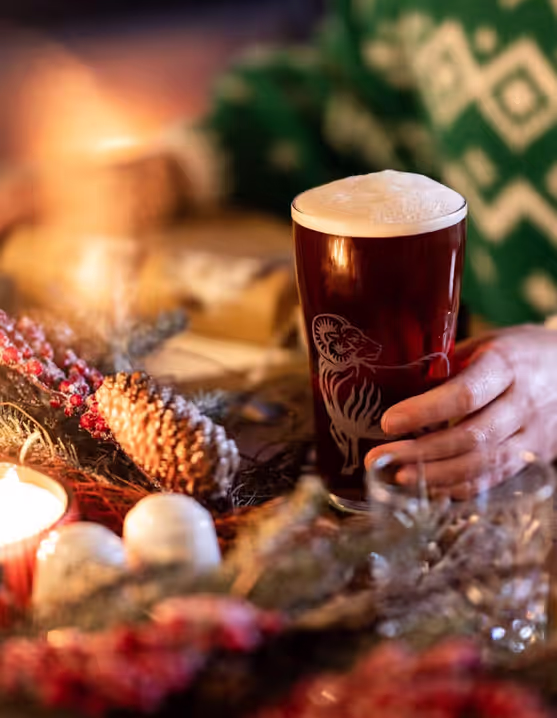 person holding a pint of Young's beer at a festive table
