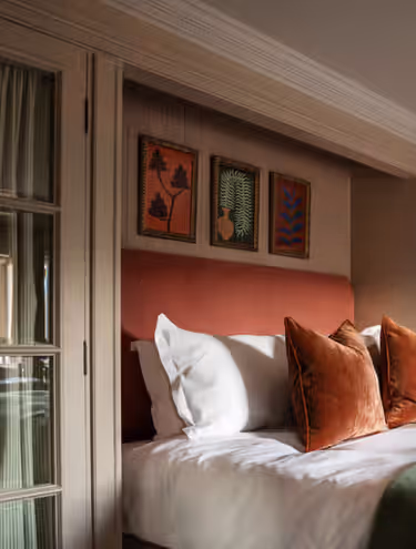 hotel bedroom with coral accent wall and pillows