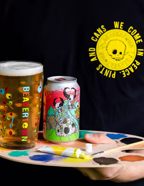 person holding a glass and can of Beavertown Lazer Crush AF IPA on a painting palette