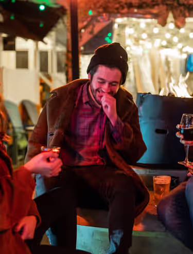 group of friends sharing drinks and laughing at an outdoor pub patio