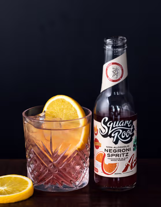 glass and bottle of Square Root Non-Alcoholic Negroni Spritz