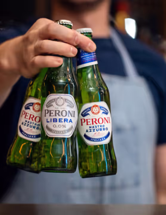 person holding three bottle of Peroni Libera