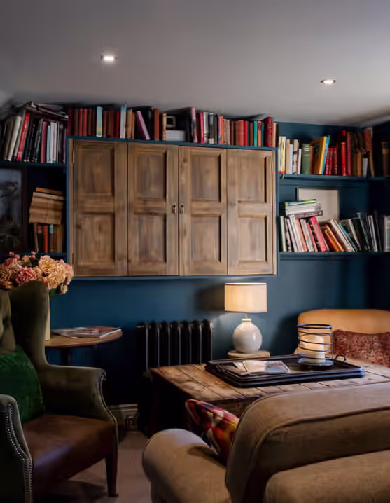 living room with blue walls, bookshelves, a couch and padded chairs