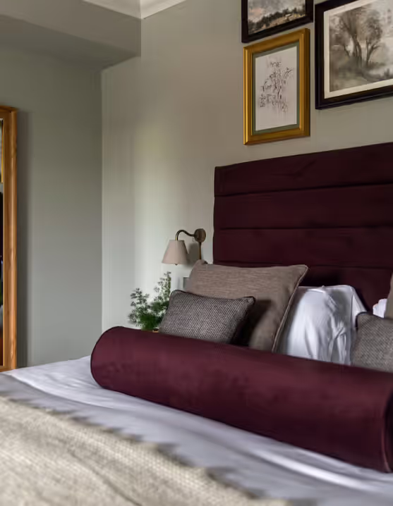 bedroom with paintings and bed with burgundy headboard and pillows