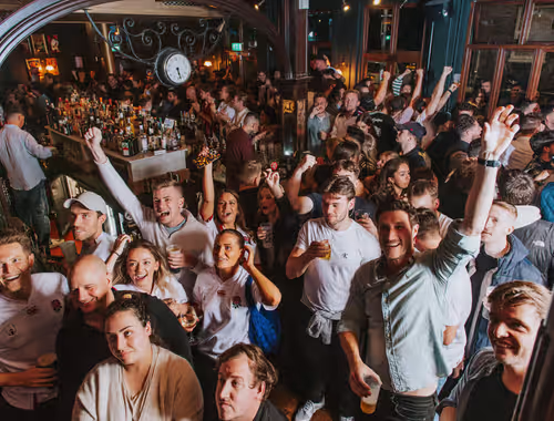 group of people drinking and cheering in a Young's pub