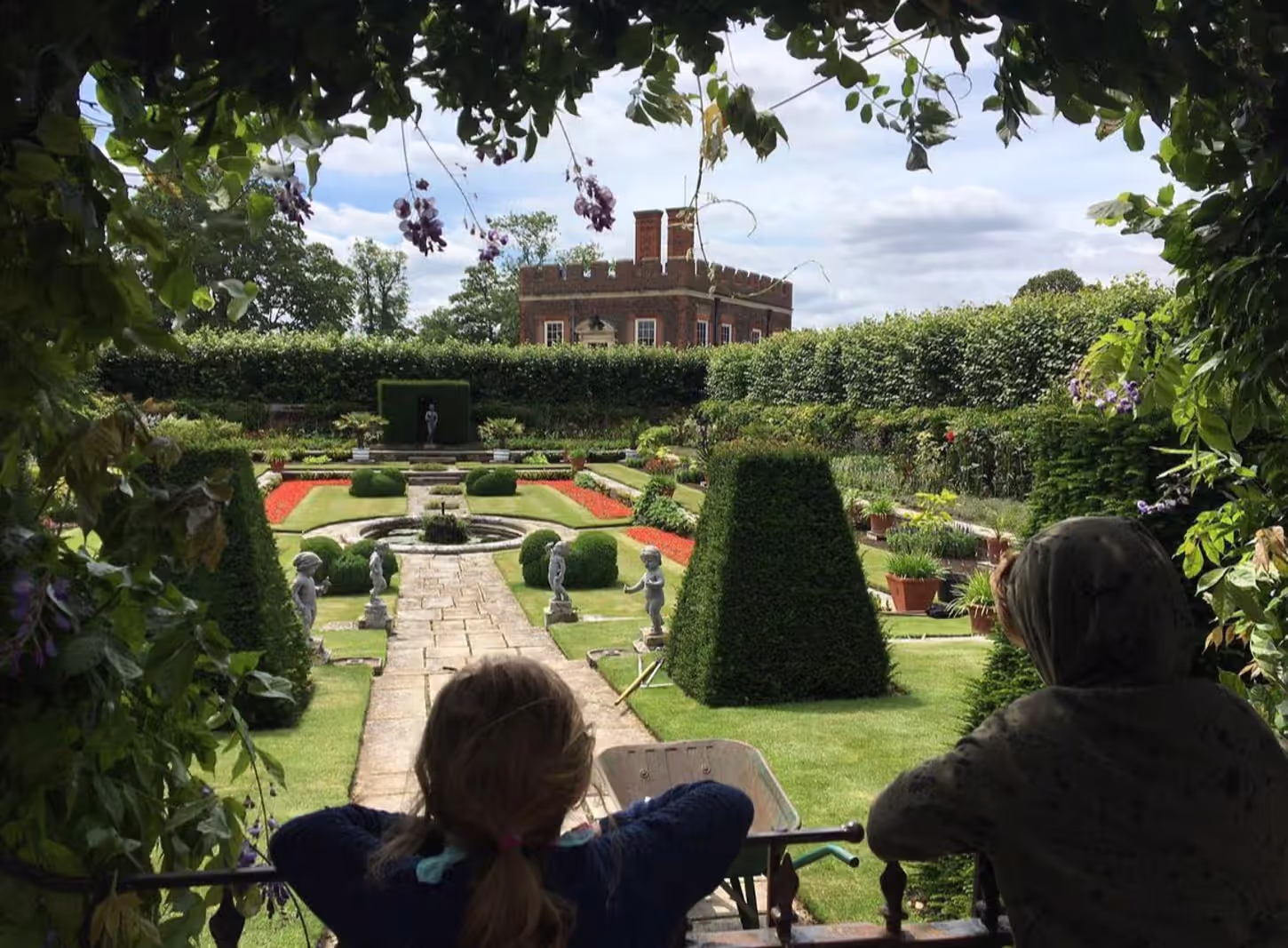 two people leaning on a railing overlooking a garden