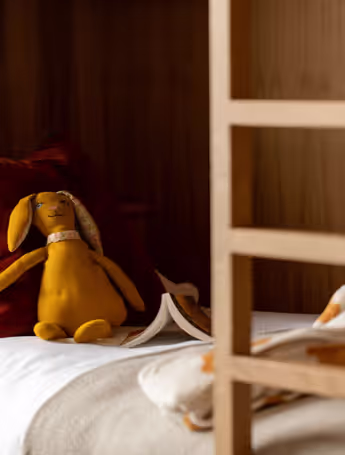 yellow stuffed bunny on a bunk bed with a book and a blanket