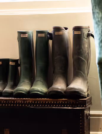 Hunter boots lined up on a wooden chest