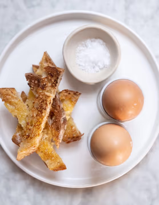 plate of two soft-cooked Burford Brown eggs with a slice of toasted sourdough bread and salt