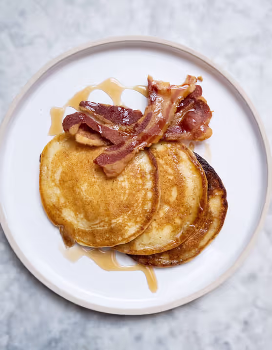 plate of bacon and buttermilk pancakes with maple syrup
