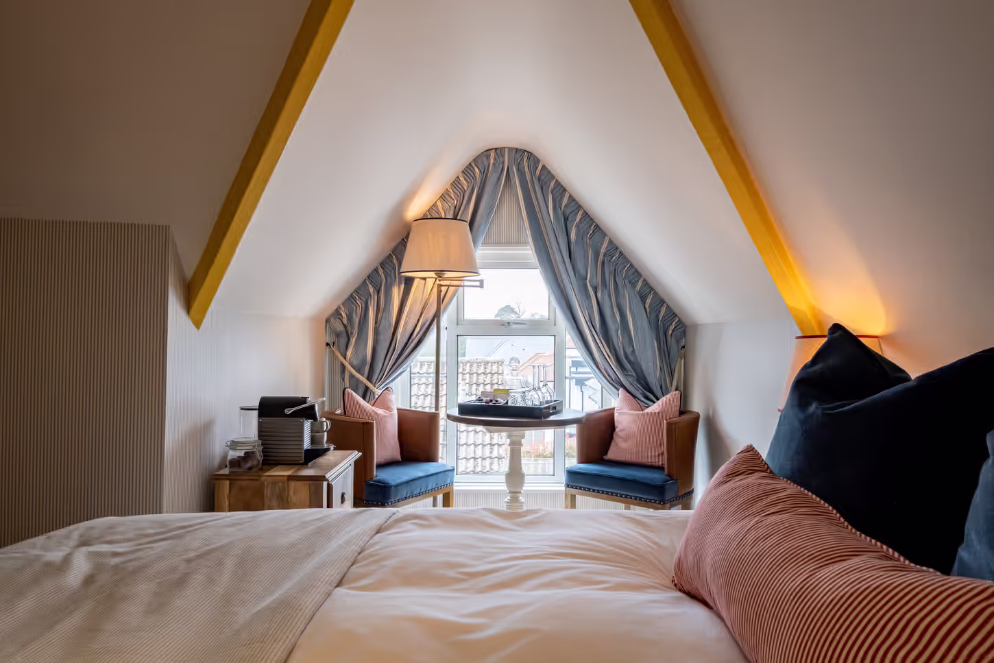 bright attic bedroom with a comfortable bed and a seating area by the window