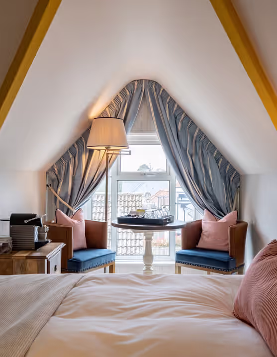 bright attic bedroom with a comfortable bed and a seating area by the window
