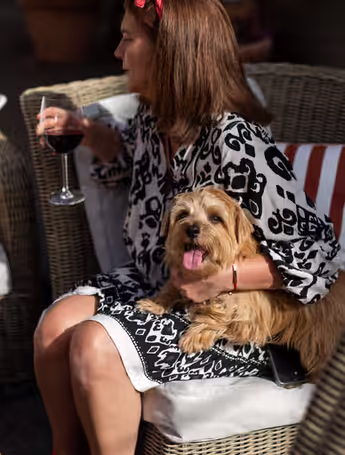 woman enjoys glass of wine with two Cairn Terriers