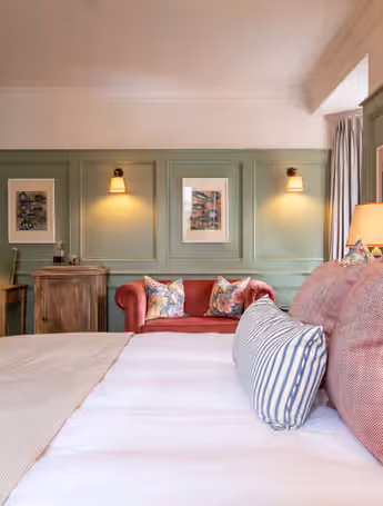 spacious hotel room with a comfortable bed, a red sofa, and a desk area