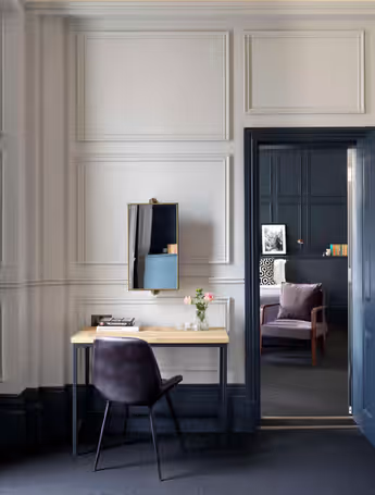 well-lit hotel room with a desk, chair, and an open door leading to a bedroom
