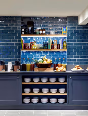 hotel kitchen area with blue tile walls and shelves filled with food