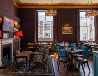 upstairs private dining area with tables and chairs across the room and a TV on the wall