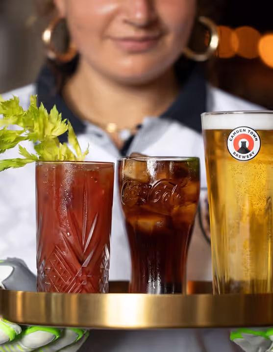 woman with sports gloves holding three drinks on a tray