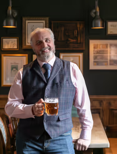 Young's general manager smiling while holding a pint of Young's beer