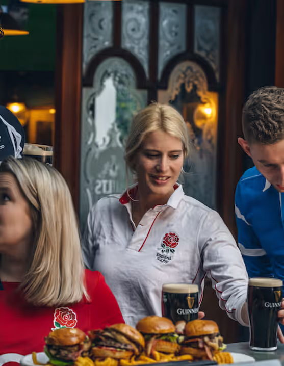 group of friends sharing pints of Guinness, burgers, and fries