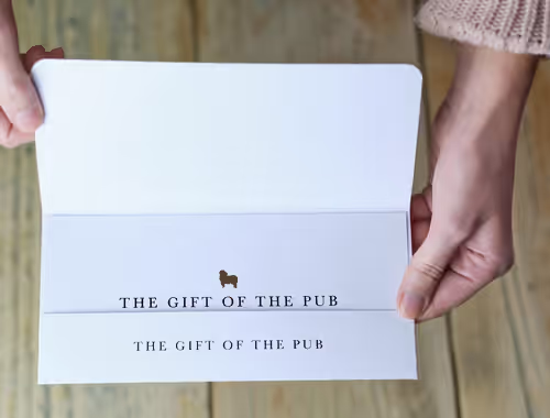 person holding an envelope that reads "Gift of the Pub"