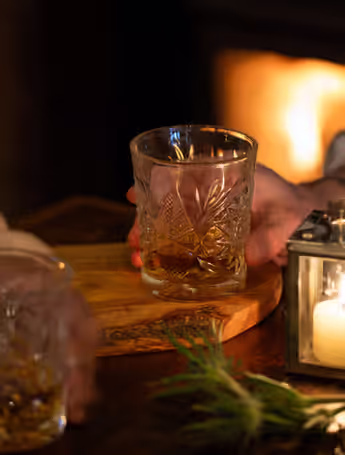 glass of liquor on a wooden tray with candles