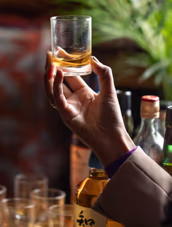 person inspecting a glass of whiskey