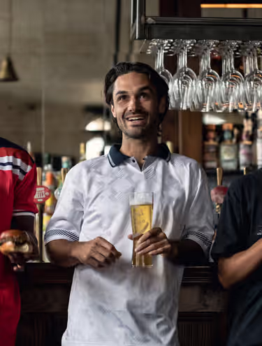 three friends watching the game with beers at a Young's pub