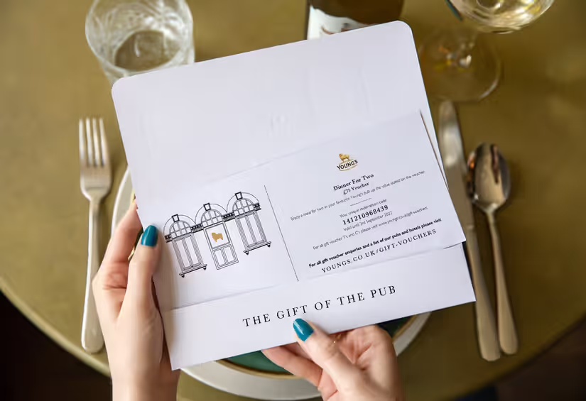 person holding a Young's gift voucher for dinner at a Young's pub