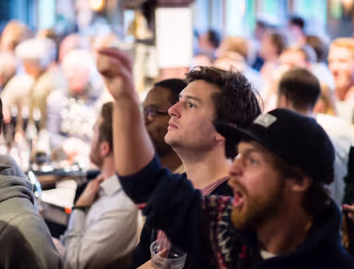 people cheering and watching a game at a Young's pub