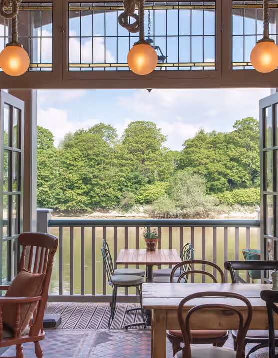 restaurant interior with tables and chairs overlooking the river and woods