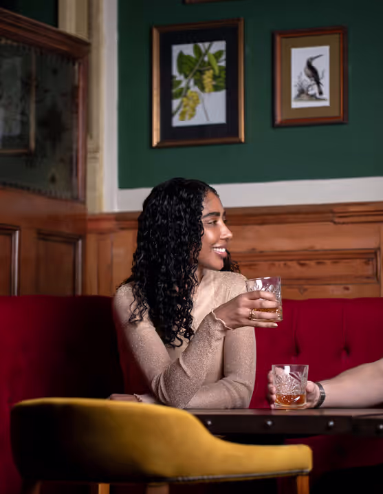 smiling woman sharing a drink with a friend at a Young's pub