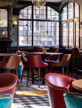 cozy pub interior with red chairs and checkered floor
