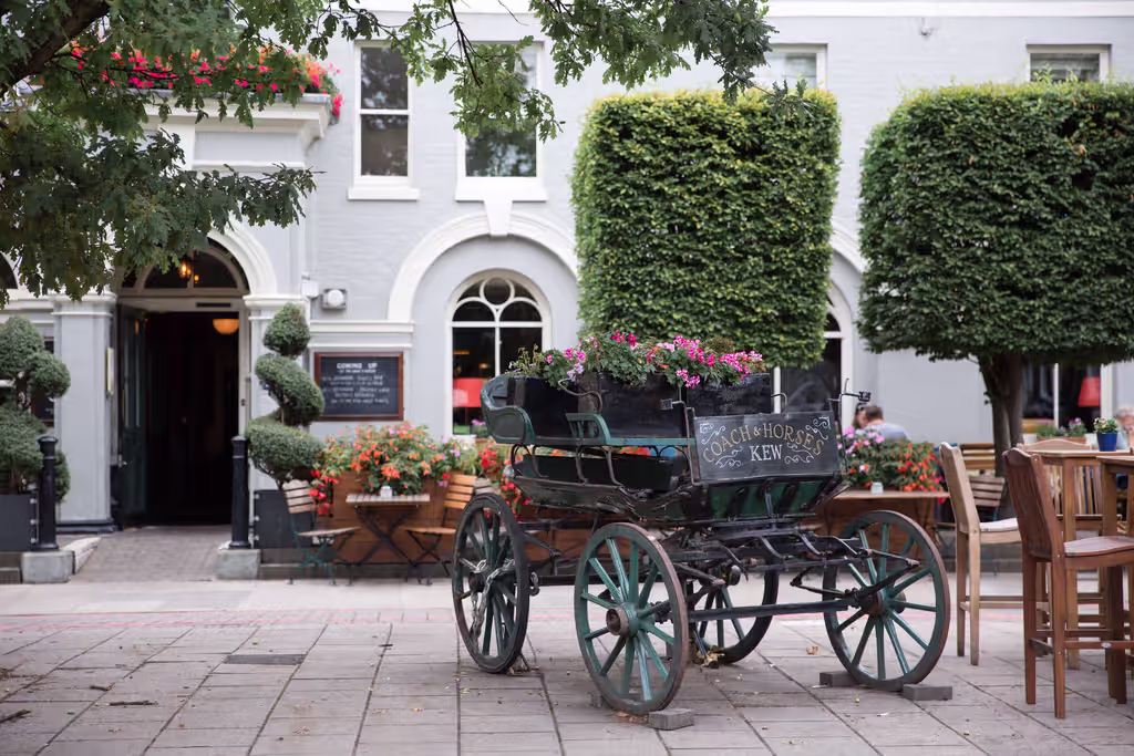 the Coach & Horses pub in Kew with outdoor seating and a horse-drawn carriage