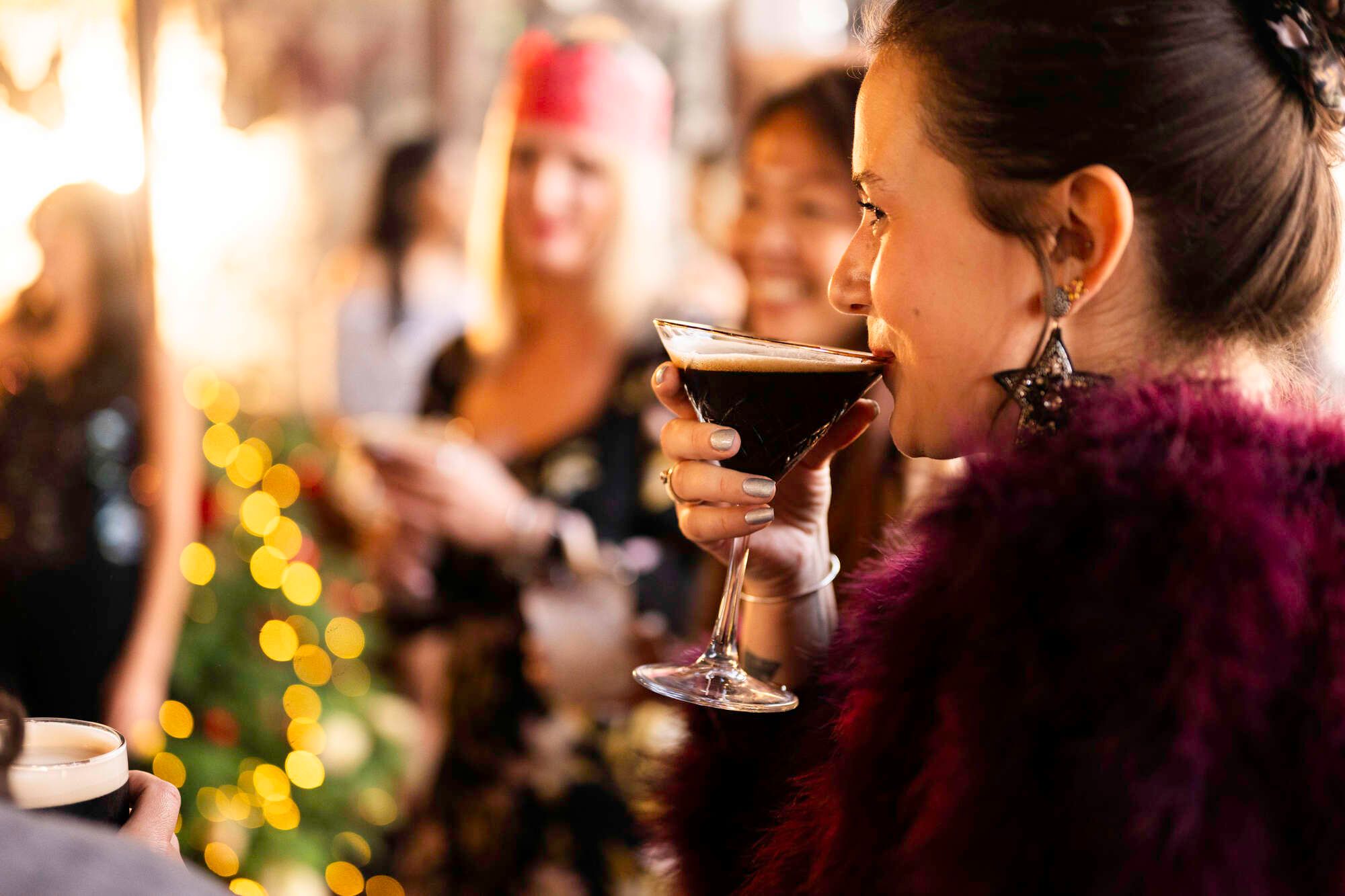 Woman enjoying espresso martini cocktail at a Christmas party at a Young's pub